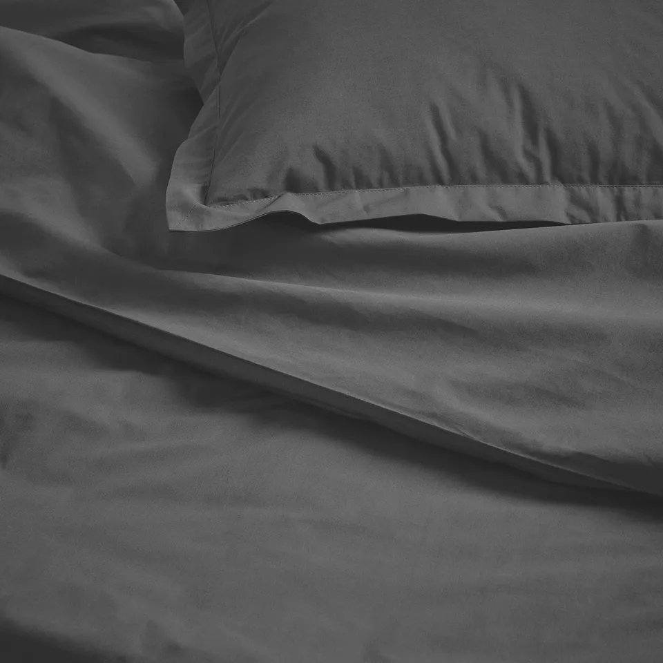 Dark grey duvet cover set, crisp and neatly folded, showcasing high-quality cotton percale weave, with pillowcases featuring decorative flanges.