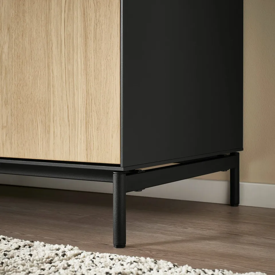 Modern black and wood sideboard with sleek lines on hardwood floor and rug.