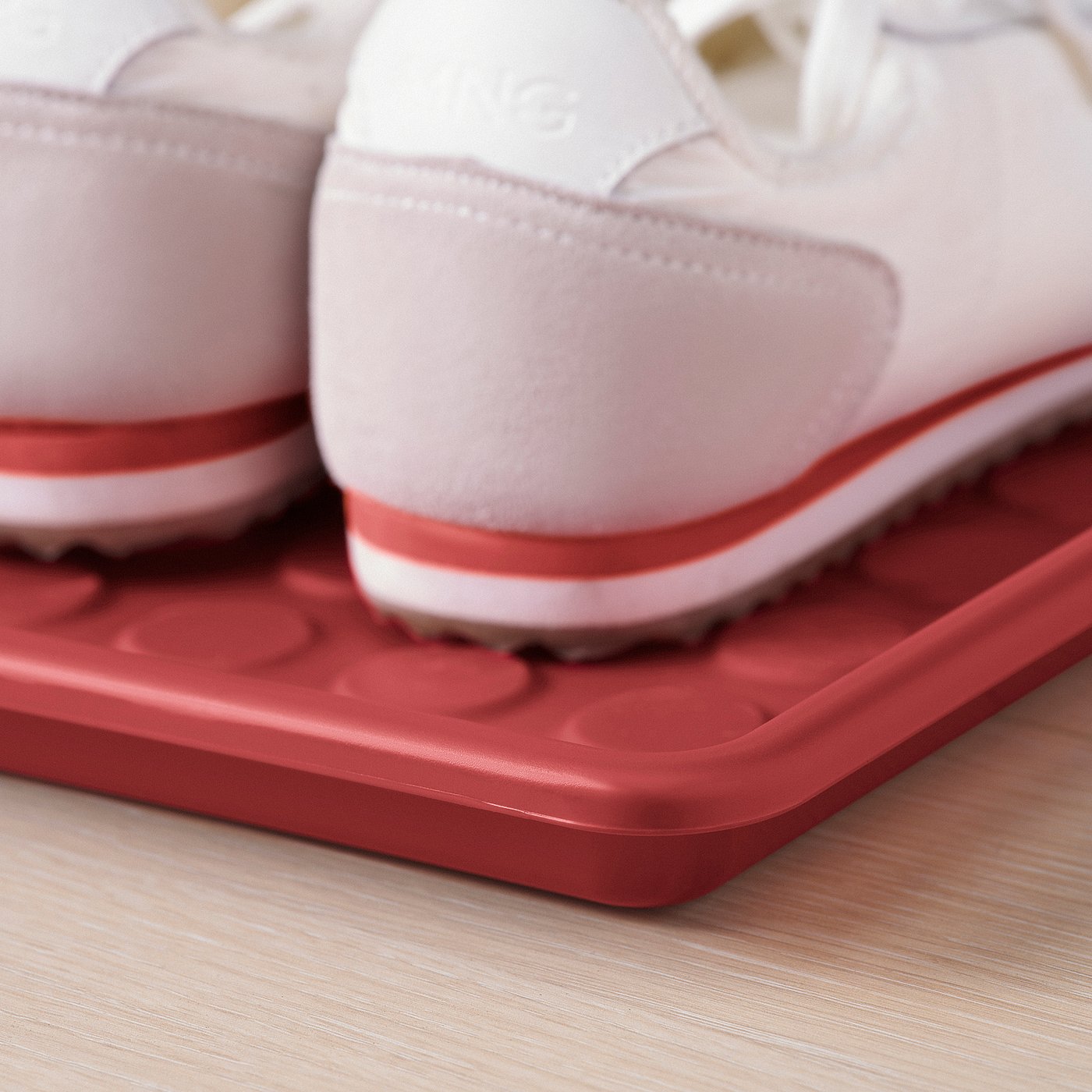 Close-up of red shoe mat with clean, modern design.