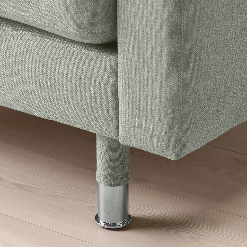 Modern light grey fabric sofa with chrome legs on wooden floor.