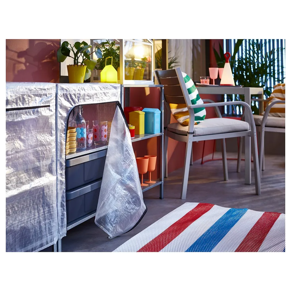 A grey metal HYLLIS shelving unit with a transparent cover, holding colourful plant pots and glasses.