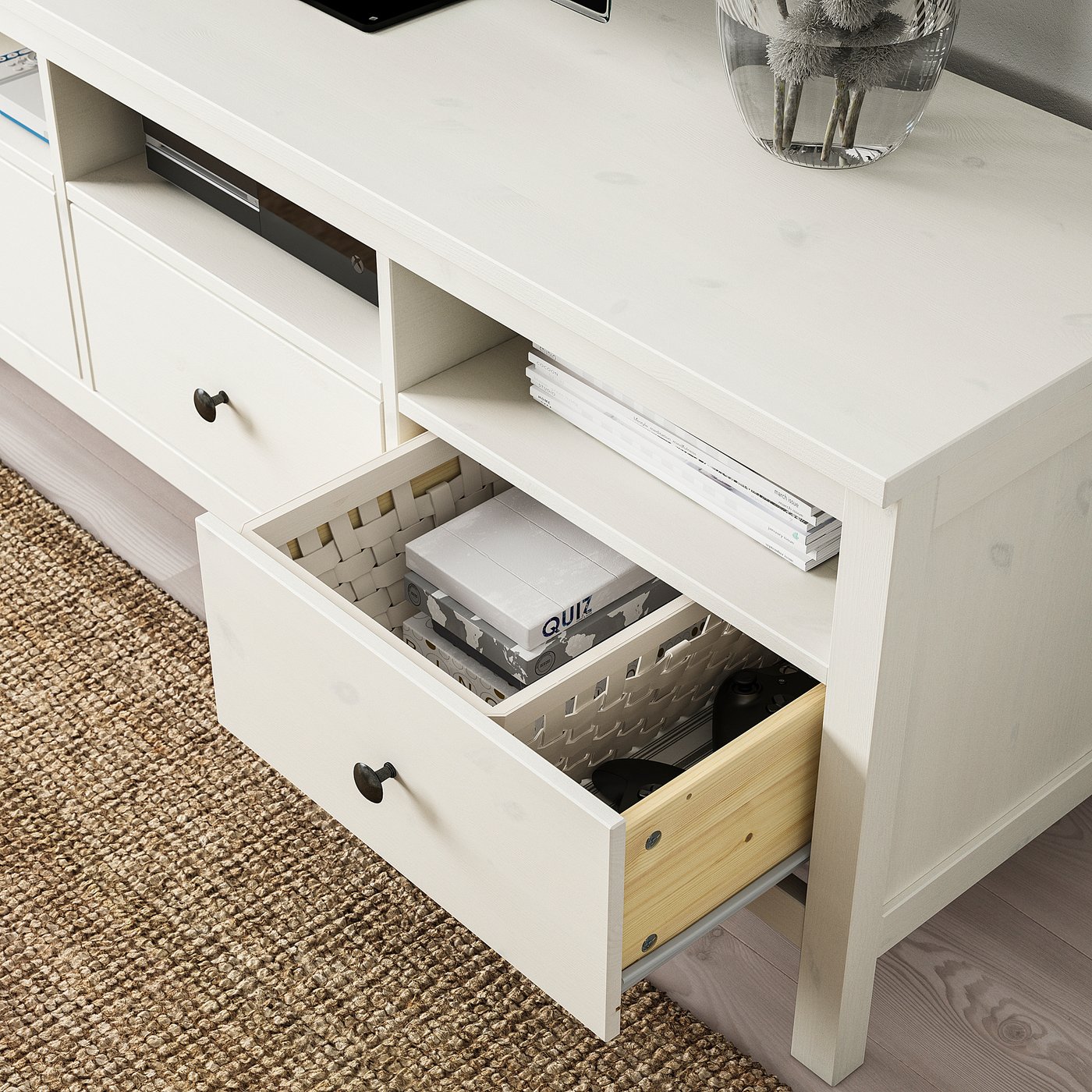 White tv bench drawer open, showcasing organised storage with wooden dividers holding game boxes and remote control.