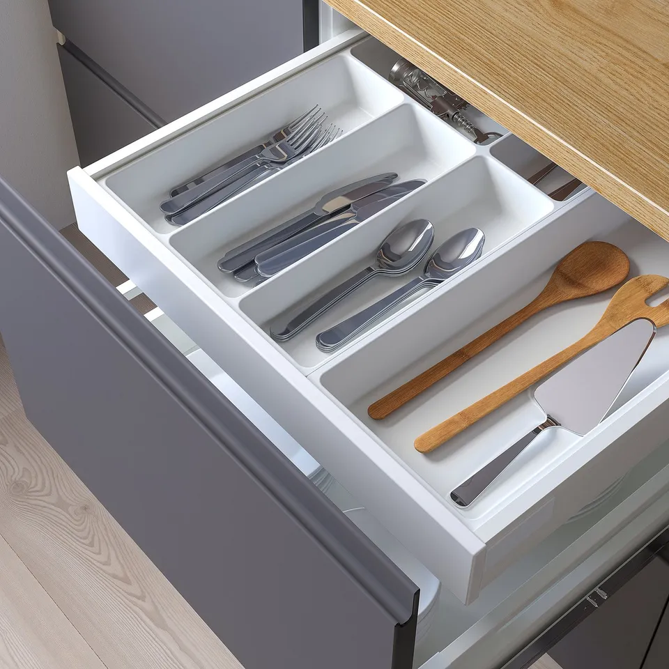 Organised cutlery drawer with separate compartments for forks, knives, spoons, and large wooden utensils.