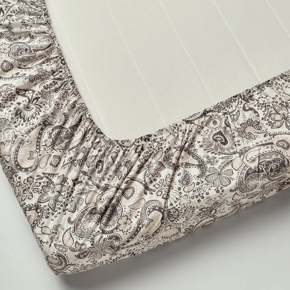 Fitted sheet with paisley pattern, elastic edging for mattresses up to 26 cm thick.