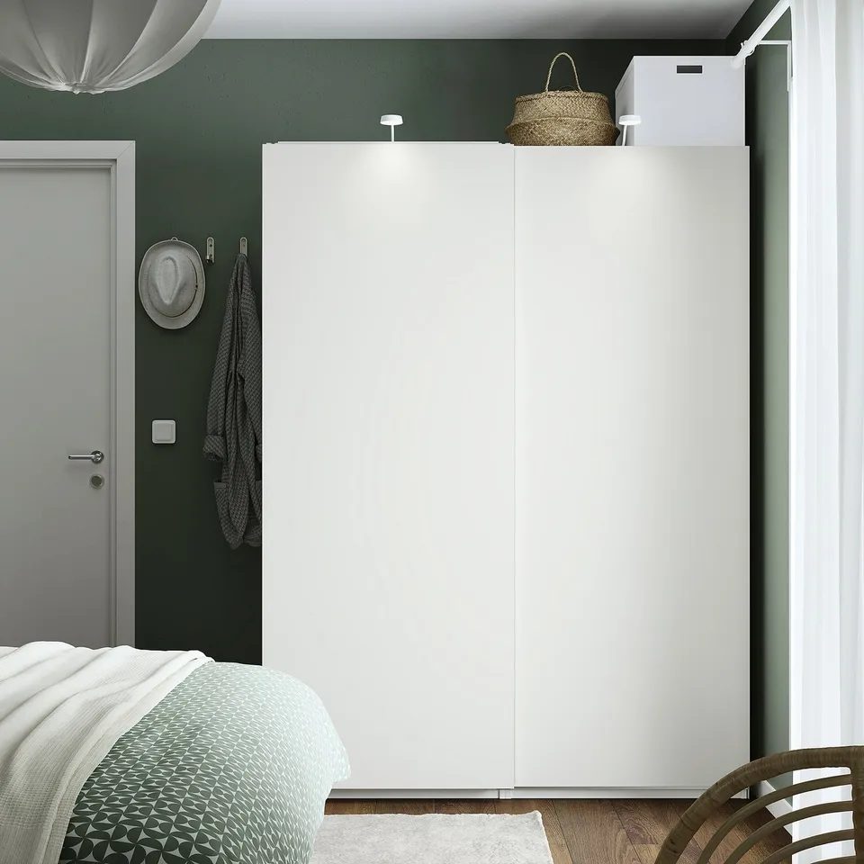 Modern bedroom with large white PAX wardrobe, green walls, and patterned bed.