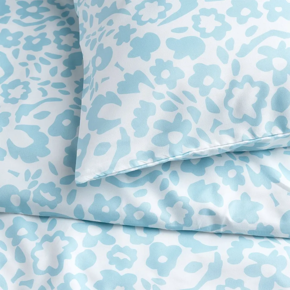 Light blue floral fabric close-up; soft, modern design; crisp details; recycled polyester.
