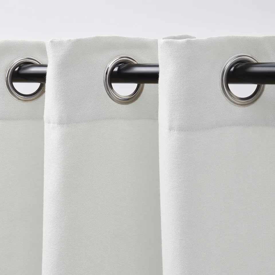 White curtains with eyelets hanging, allowing light and providing privacy.