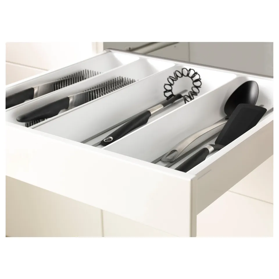 White kitchen drawer with compartments holding knives and utensils.