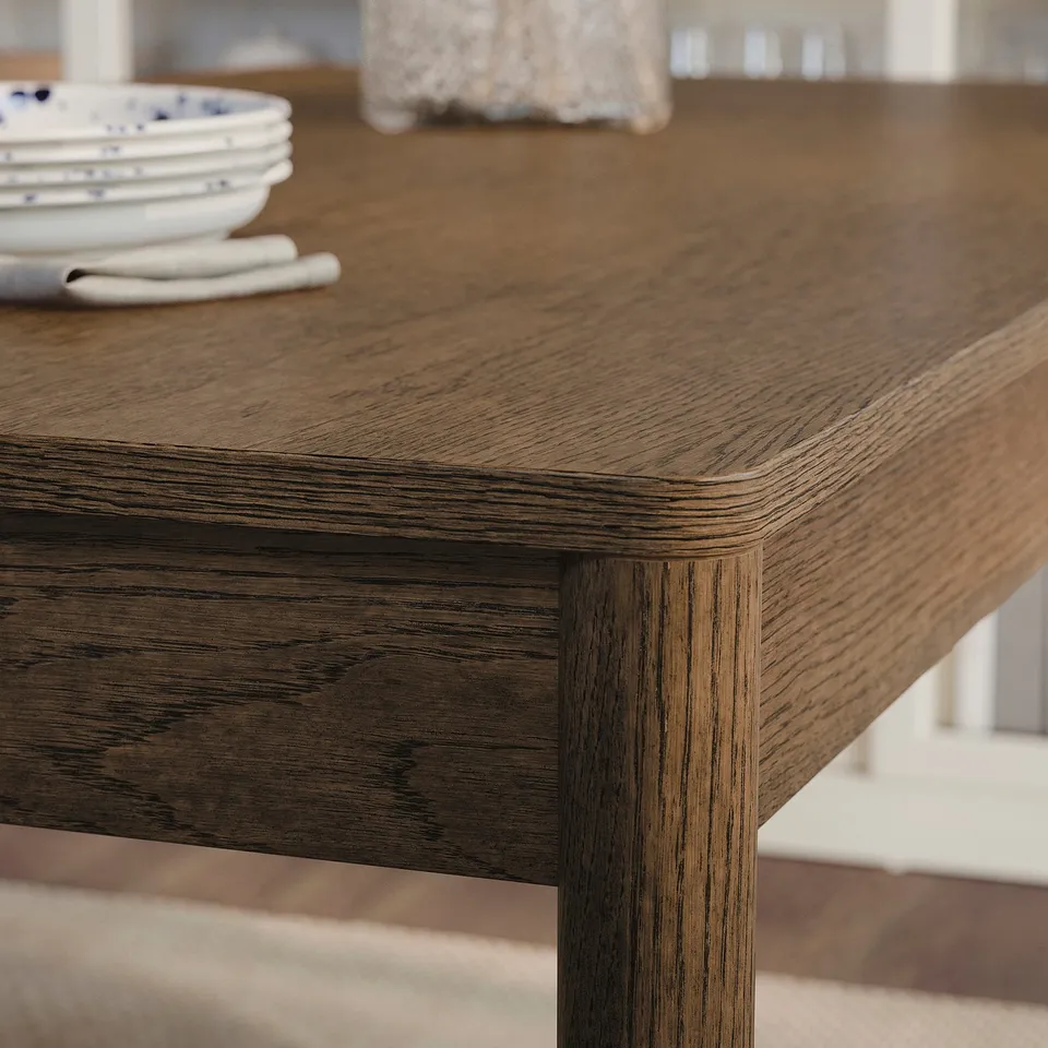 Close-up of a modern, high-quality wooden table. Smooth, rounded edges and natural wood grain, showcasing its sturdy and elegant design.