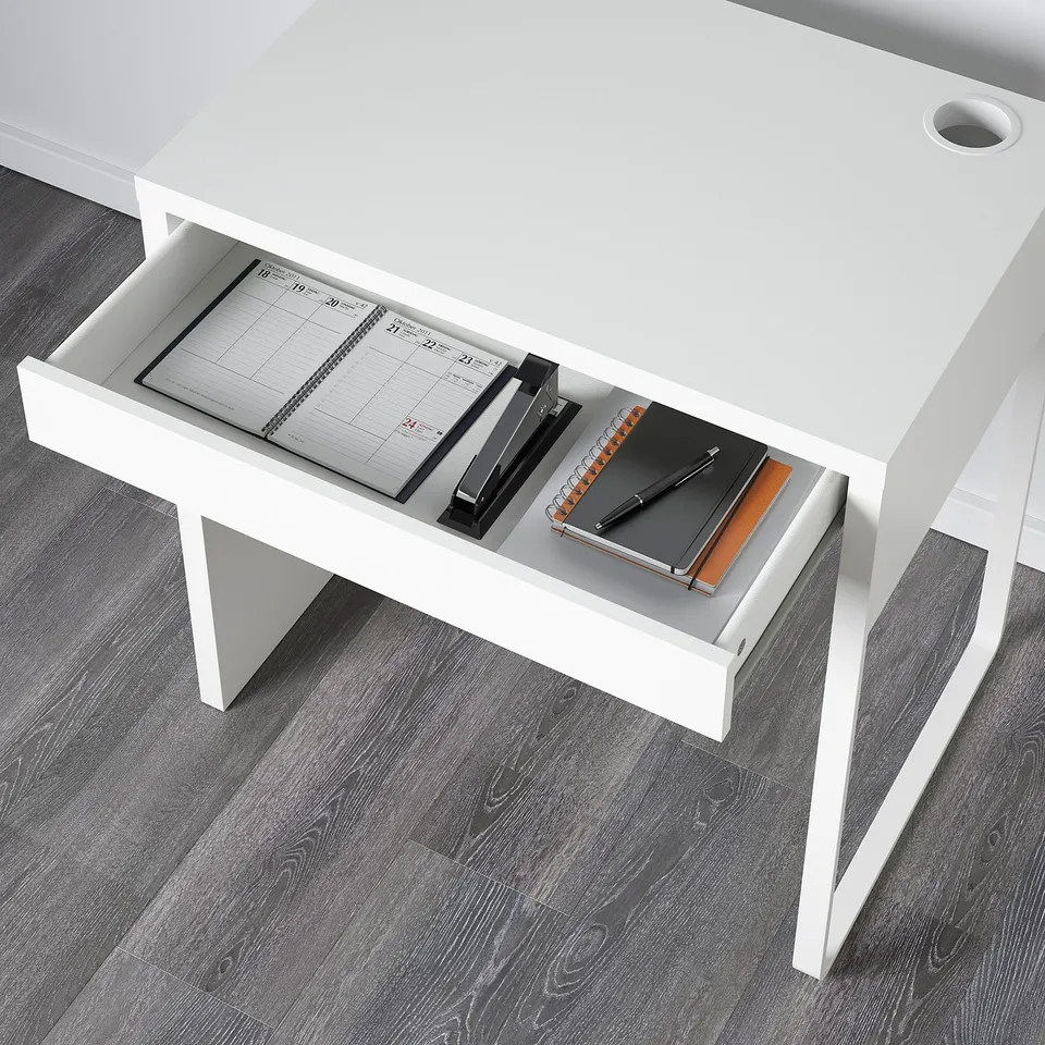 Desk drawer open with calendar, pen holder, notebooks, and pen; useful for organisation.