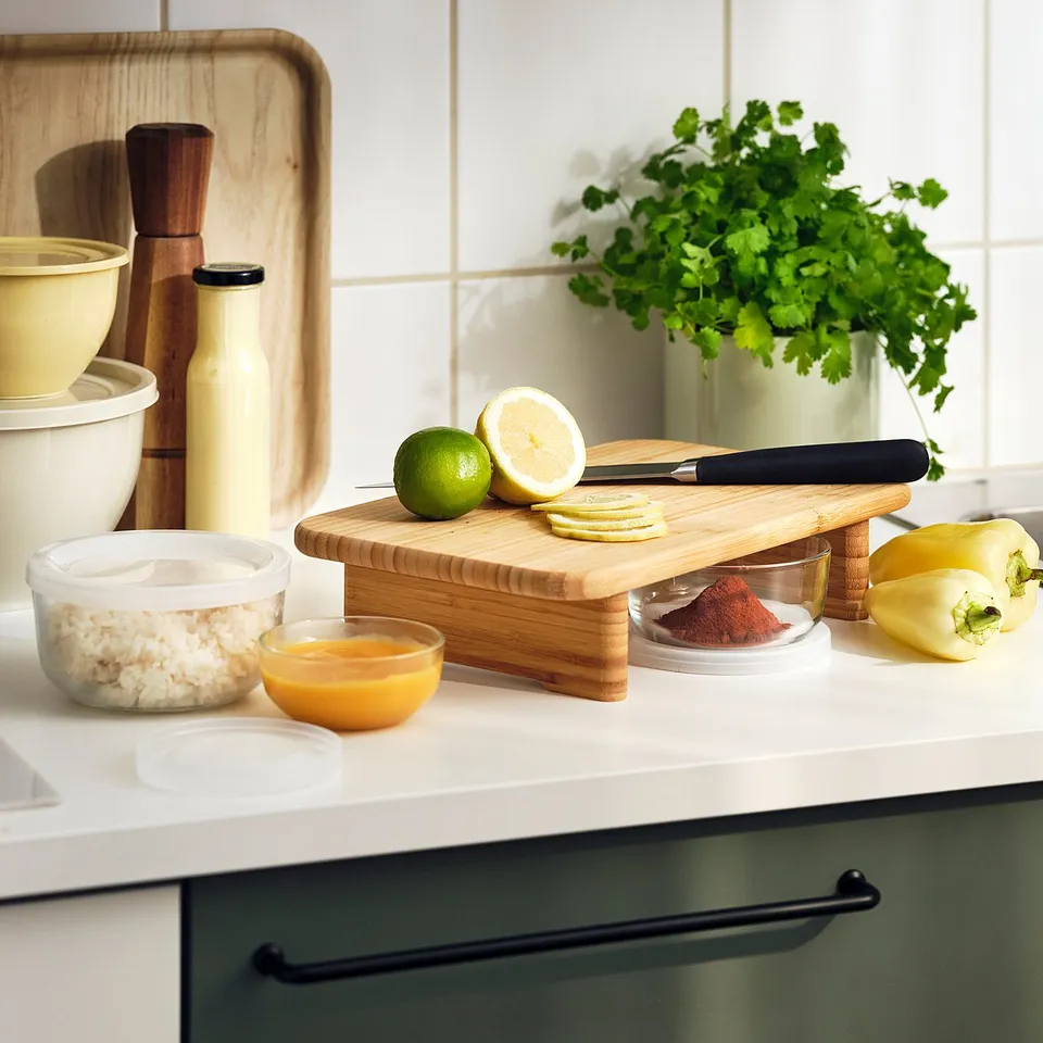Kitchen counter with limes, lemons, spices, cutting board, bowls, and plant.