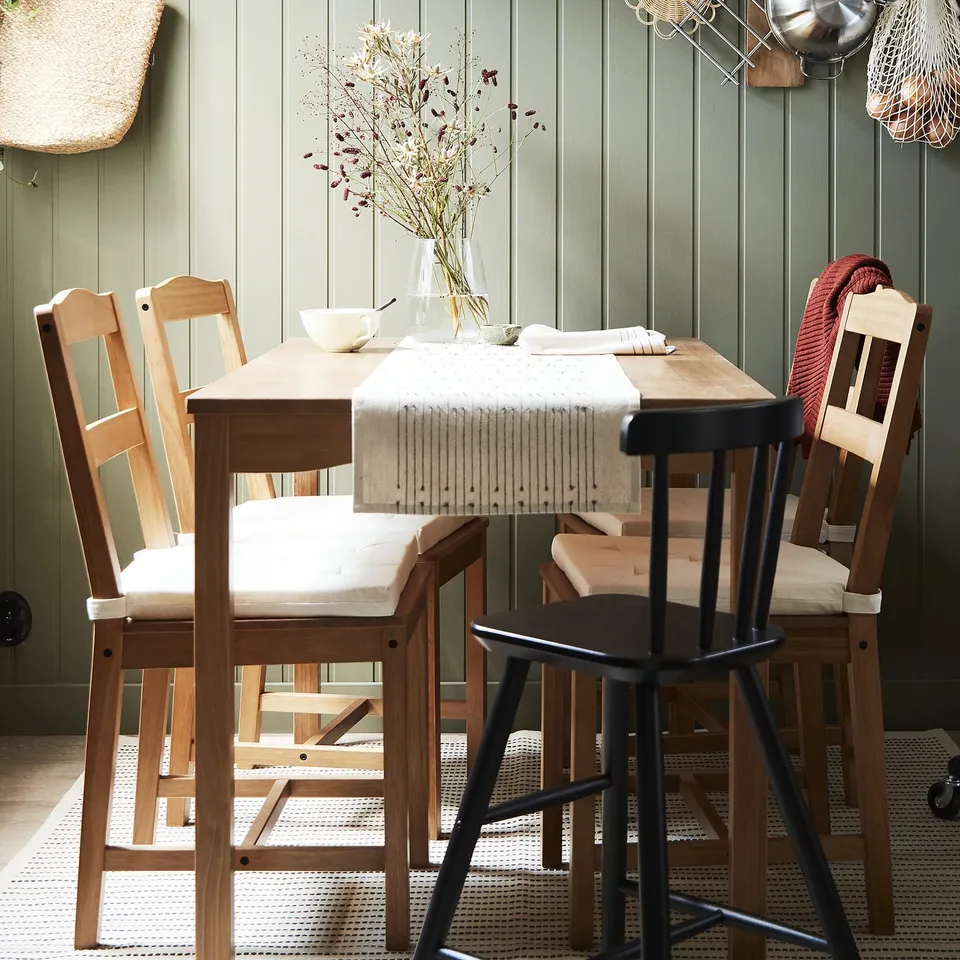 Cosy dining setup with HÄGERNÄS table, flowers, & red blanket.