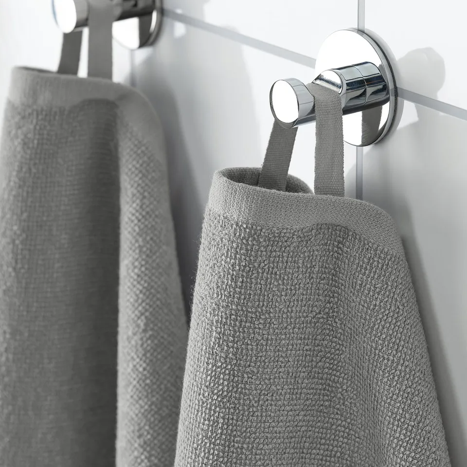 A silver towel hook holds a light grey, folded towel. Its designed for quick drying and easy storage, ideal for travel or the gym.