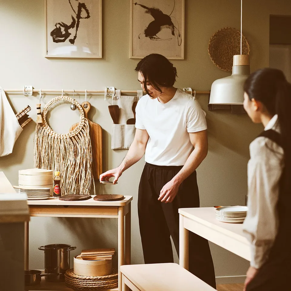 Two people cooking in minimalist kitchen with trolley.