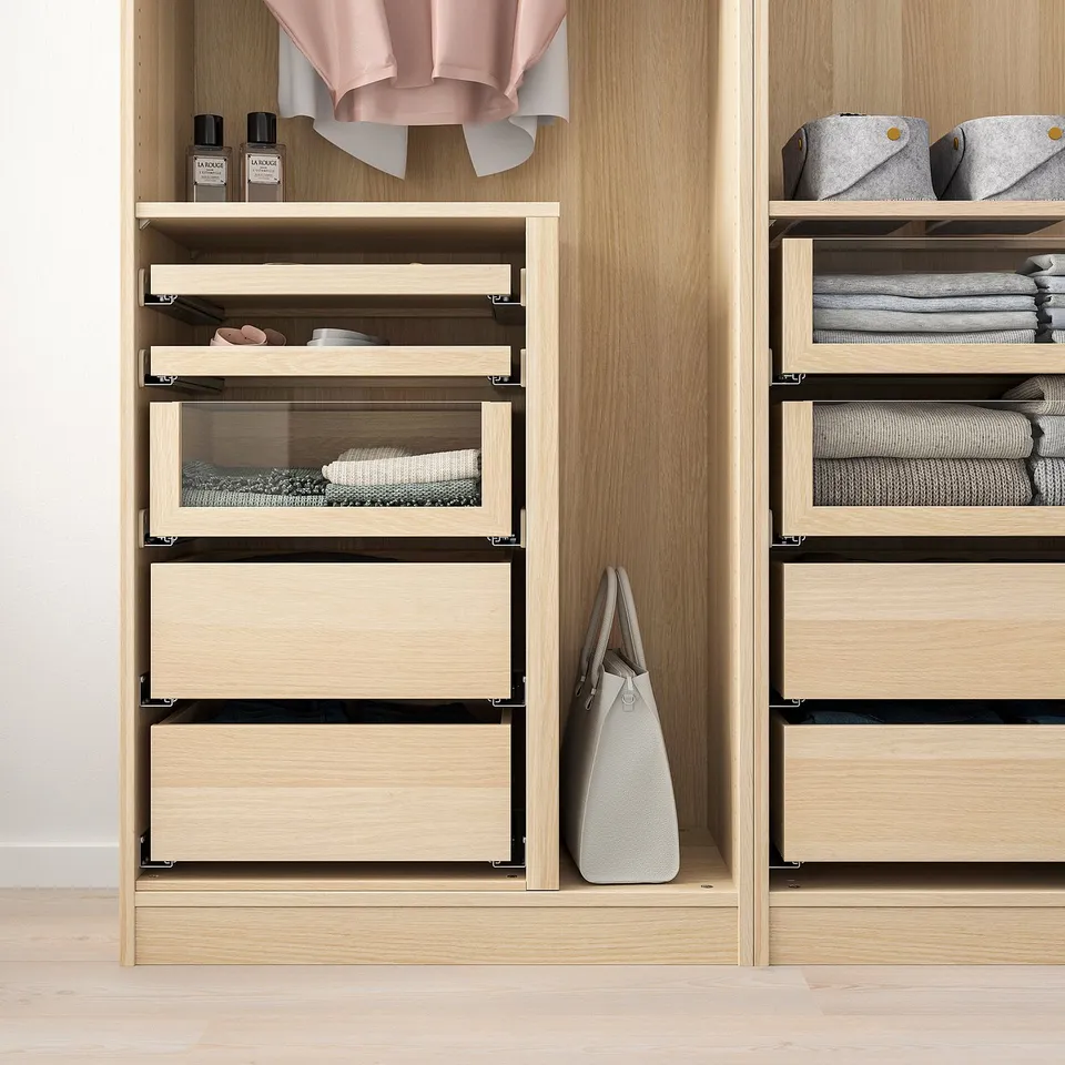 Modern wooden closet with glass-fronted drawers displaying neatly folded clothes and accessories.