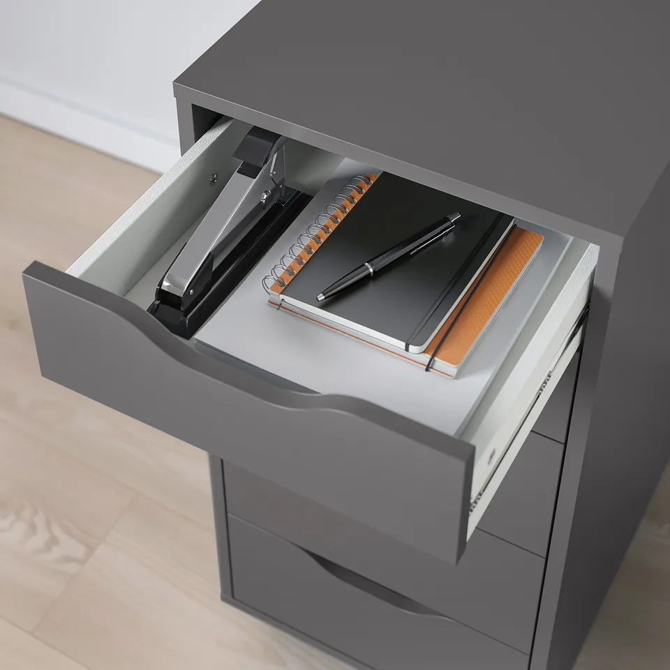 Grey ALEX drawer with notebook, pen, and stapler; stops prevent full drawer removal.