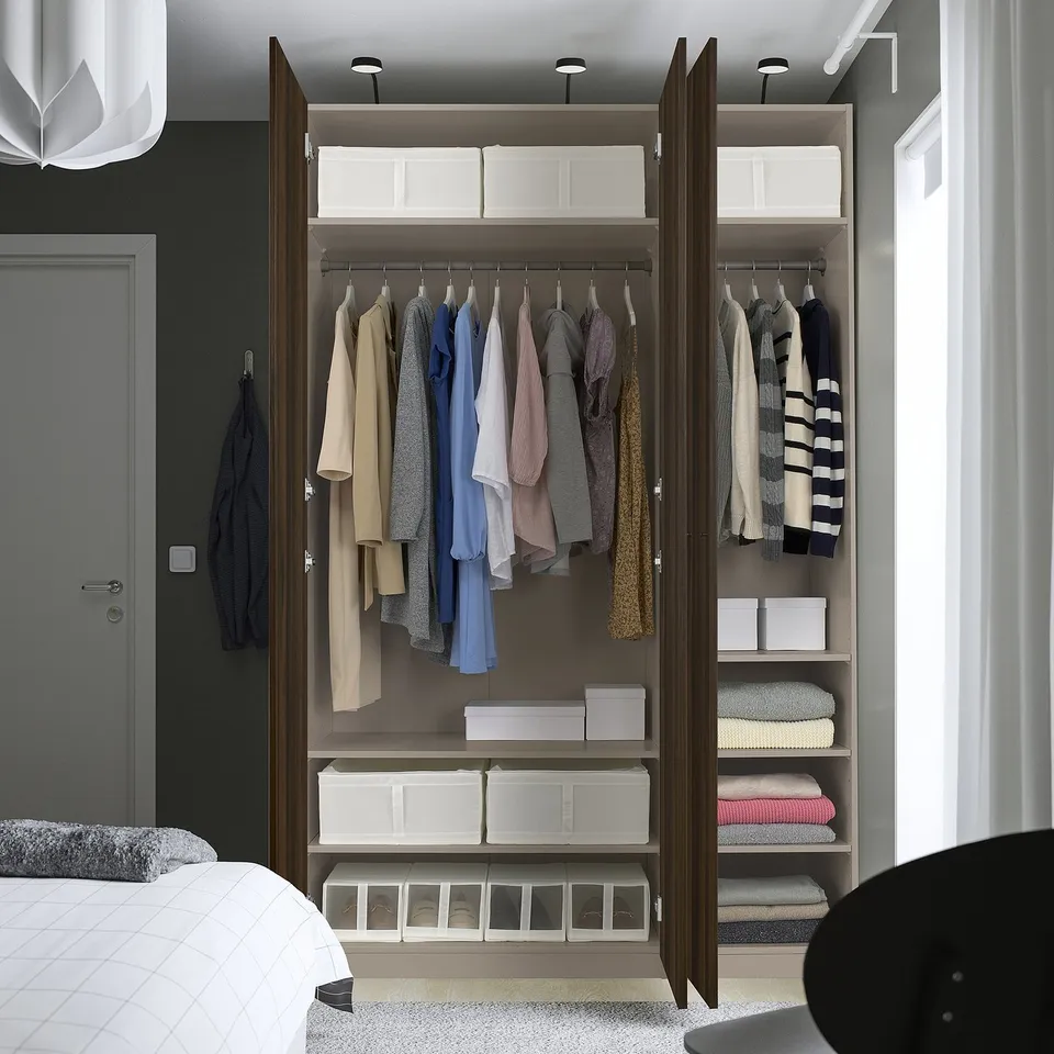 Open wooden wardrobe displaying clothes, folded items, and storage boxes.