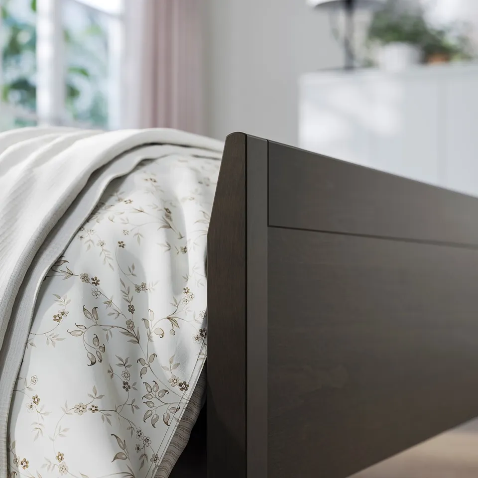 Modern bedroom scene with dark wood bed, light floral bedding, featuring headboard.