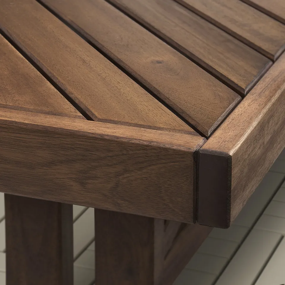 Close-up of a sturdy wooden bench. Its slats form a decorative herringbone pattern, handcrafted from durable acacia wood.