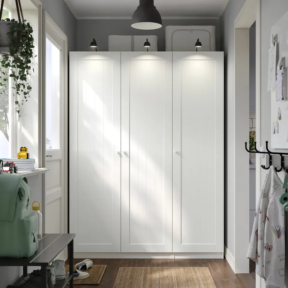 PAX wardrobe stands tall with recessed handles and lighting.