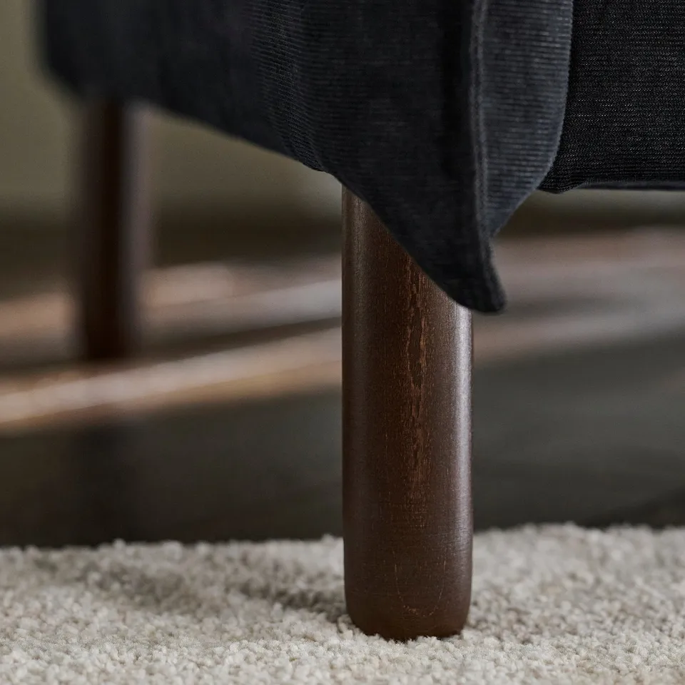 Dark sofa with sturdy, polished wooden leg
