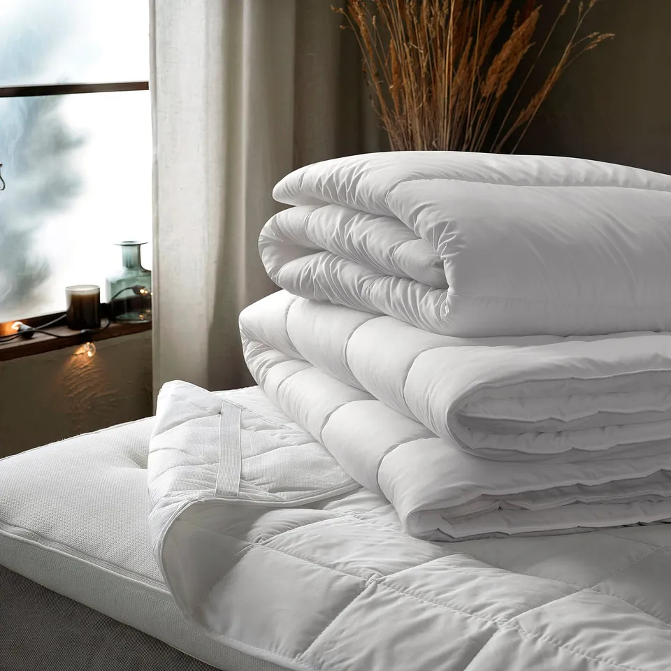 White SÄFFEROT duvet, large, neatly stacked on bed, soft, recycled material.