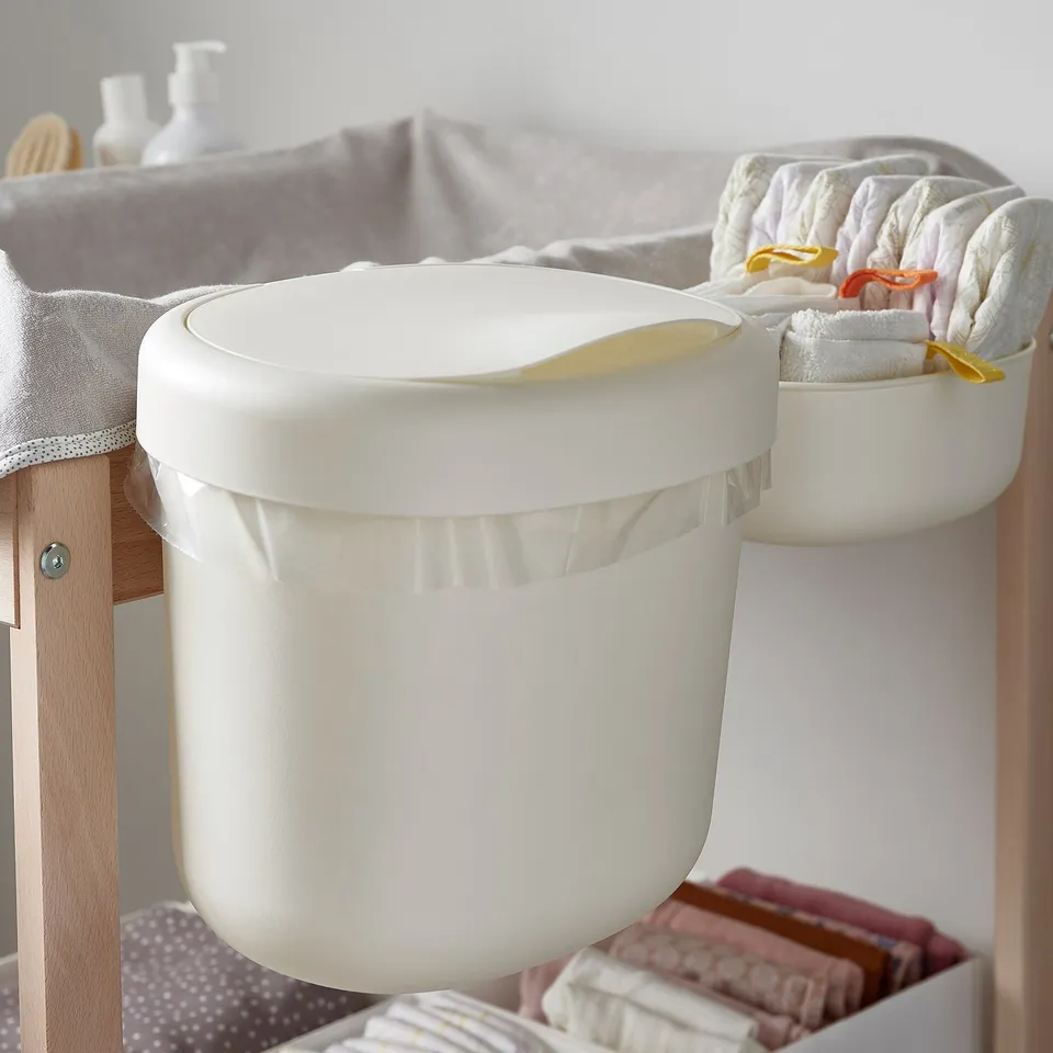 Two hanging storage baskets on a changing table: one for waste, another for towels. Handy for baby care.