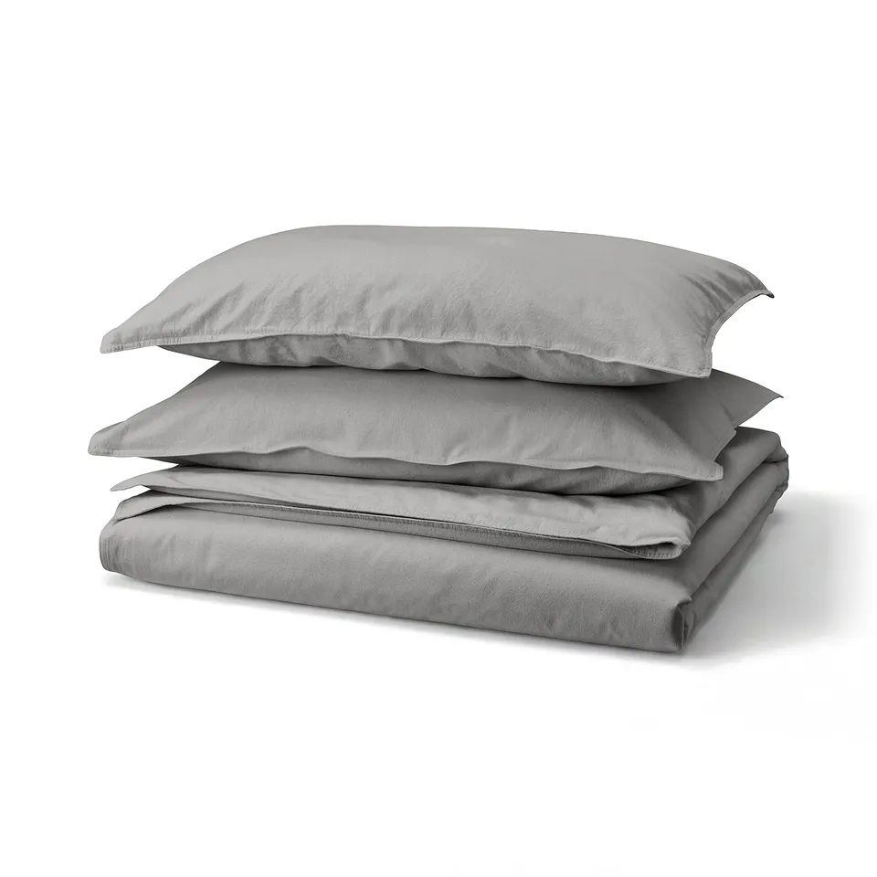 A stack of grey ÄNGSLILJA bed linens: a duvet cover and pillowcases made of soft, recycled cotton in a plain, rectangular design.