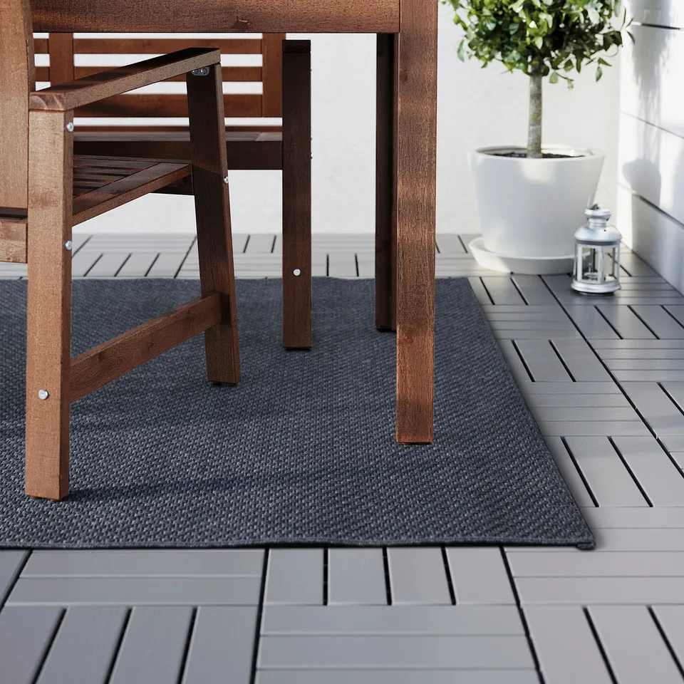 Outdoor rug under wooden furniture, adding calm and comfort.