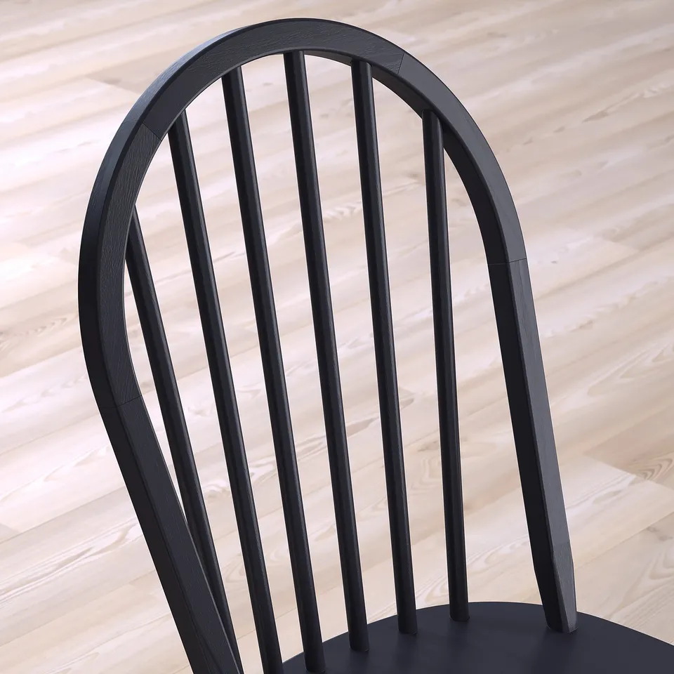 Modern black wood chair back on light floor.