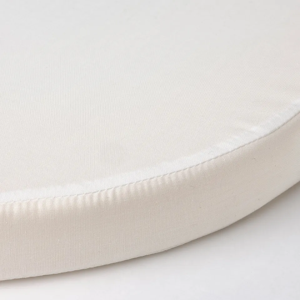 Close-up of a soft, white, round mattress with smooth fabric and clean stitching.