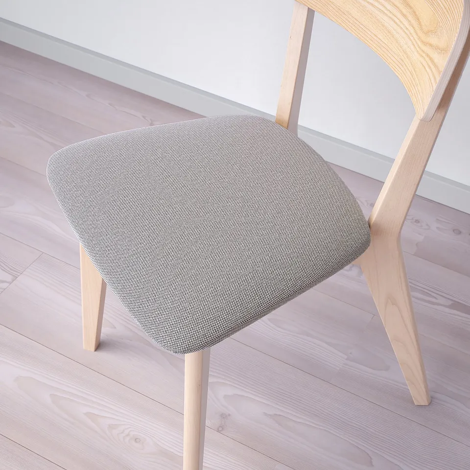 Modern wooden chair with cushioned seat on light wooden floor. High-quality, sturdy design.