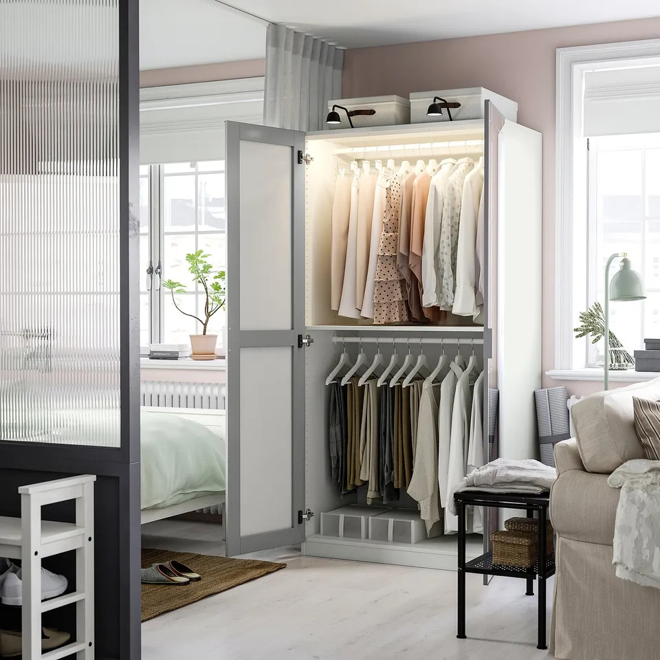 Open wardrobe displaying clothes and accessories, with mirror doors reflecting room decor.