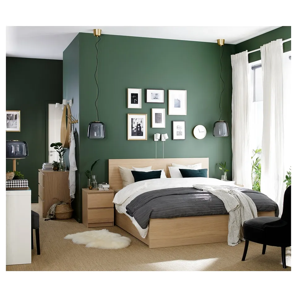 Modern bedroom with green walls, wooden furniture, and a grey bed with white details, under minimalist lighting.
