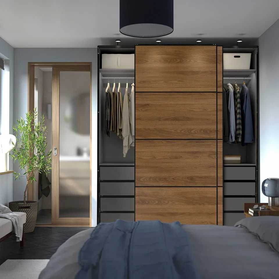 Modern bedroom with PAX wardrobe and sliding doors. Clothes visible through glass.