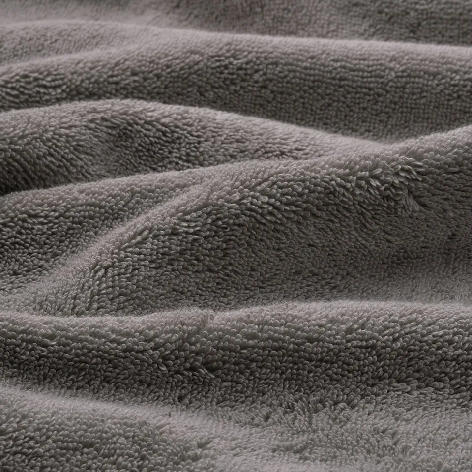 Close-up of soft, textured, grey organic cotton towels, showcasing intricate weave and plush texture, highlighting quality and comfort.