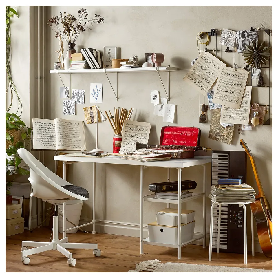 Modern home office with SPÄND white table, books, notes, plants, guitar, and decorations.
