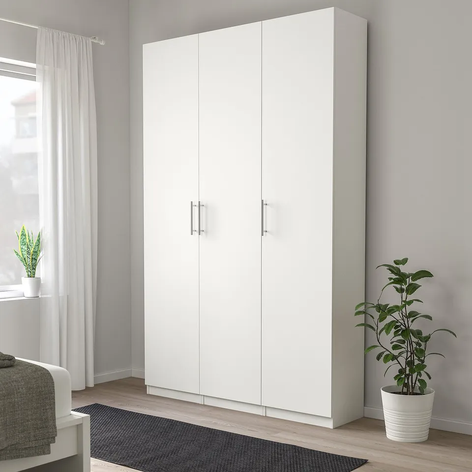 Large white wardrobe with silver handles, tall, beside plant.