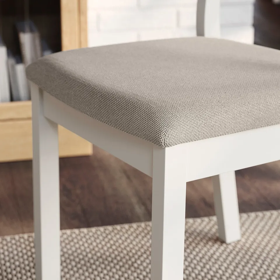 Close-up of a modern, upholstered dining chair with a cushioned seat and sleek white frame.