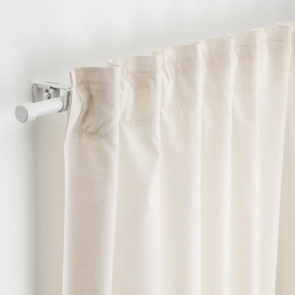 White curtain rod set with beige curtains, including connectors and holders, mounted on a plain wall.