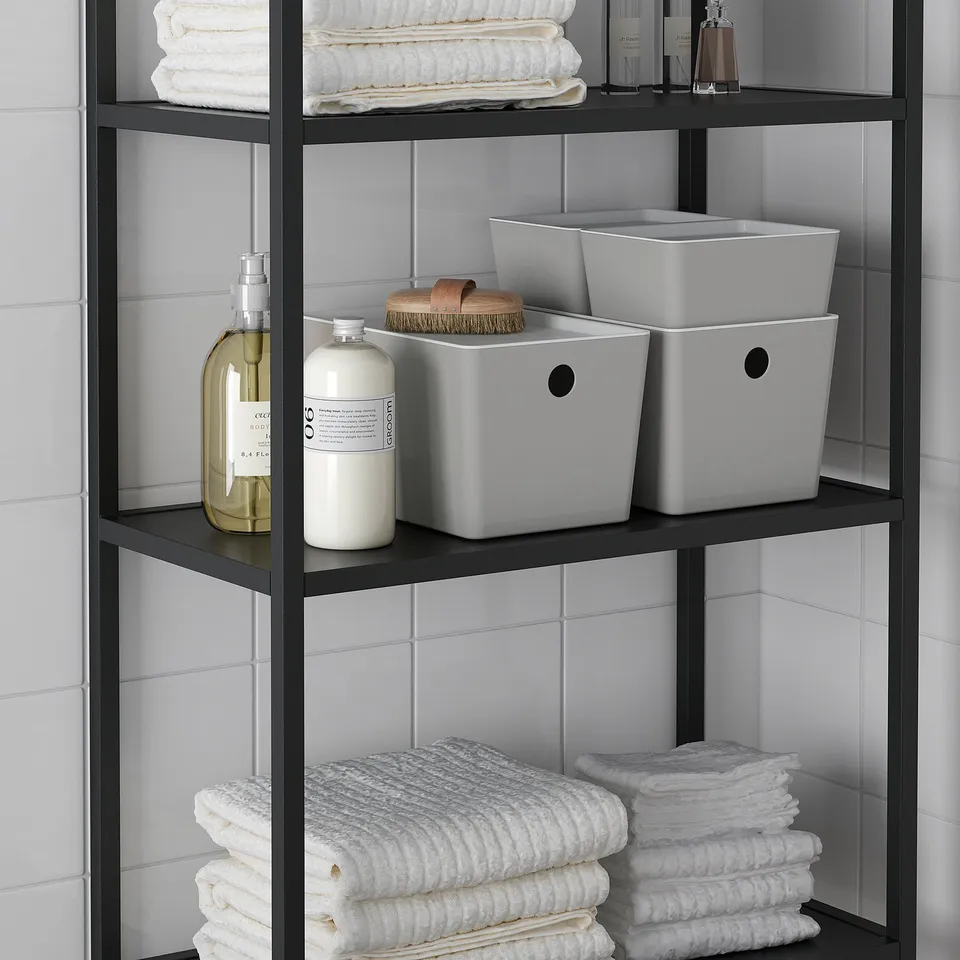 Shelf with folded towels, bottles, and grey KUGGIS storage boxes, ideal for organising bathroom or kitchen items.