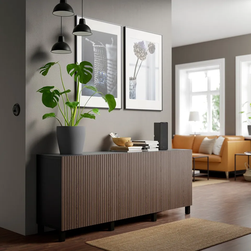 Modern living room with dark oak sideboard, books, speaker, plant. Contrasts neutral walls, complements orange sofa.