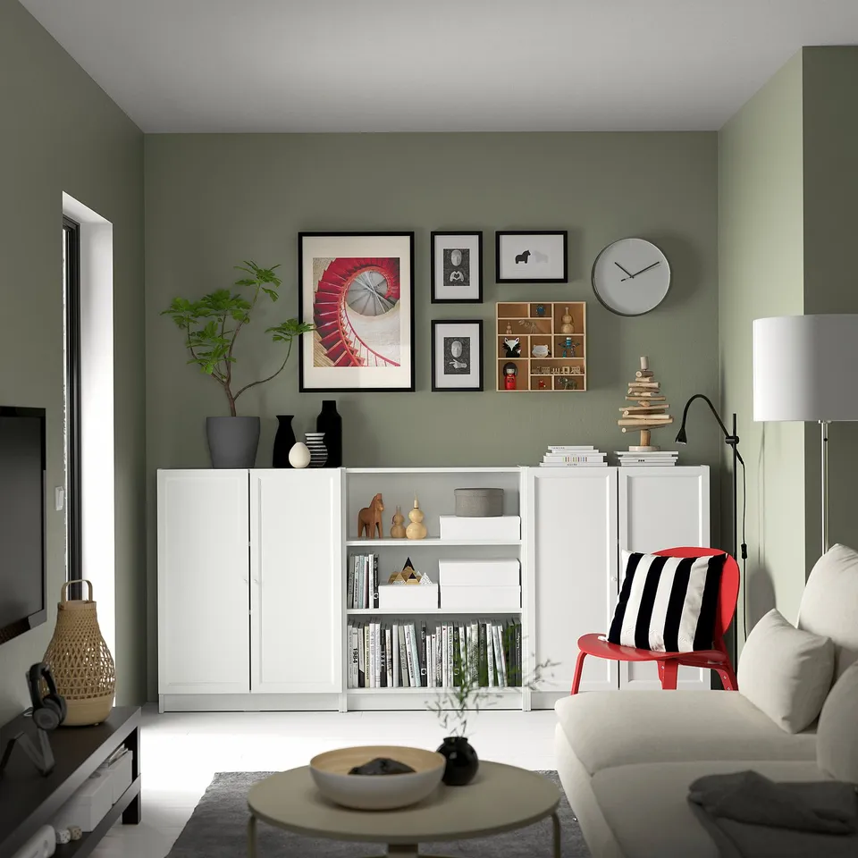 Modern living room with a white BILLY bookcase, green walls, colourful decorations, and a cosy seating area.