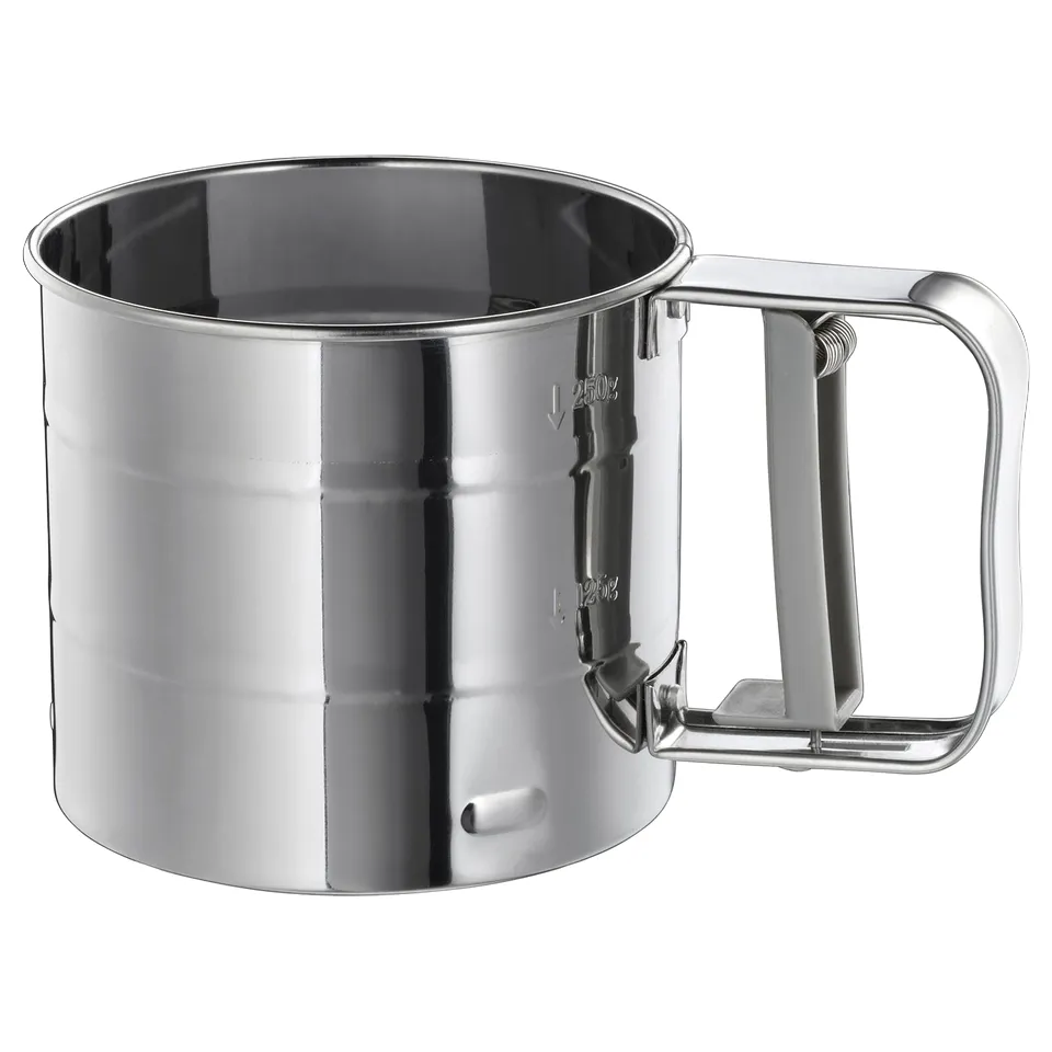Silver-colored stainless steel mug with handle, shiny surface, rectangular shape, simple design.