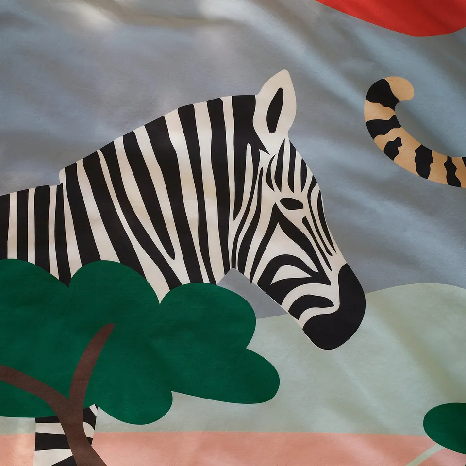 Zebra close-up, bold stripes in black and white, on soft savannah fabric, with green leaf.
