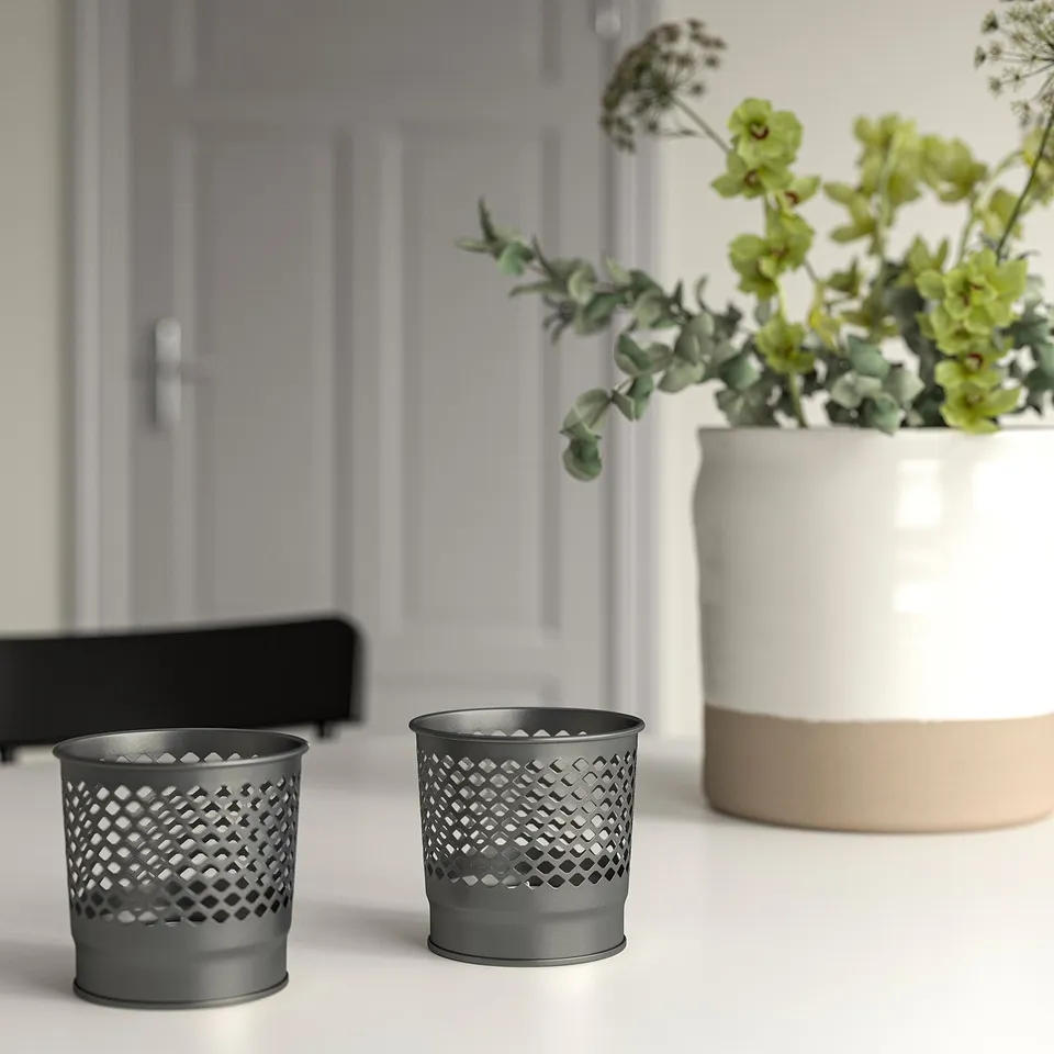 Black candle holders, plants, white surface, grey door.