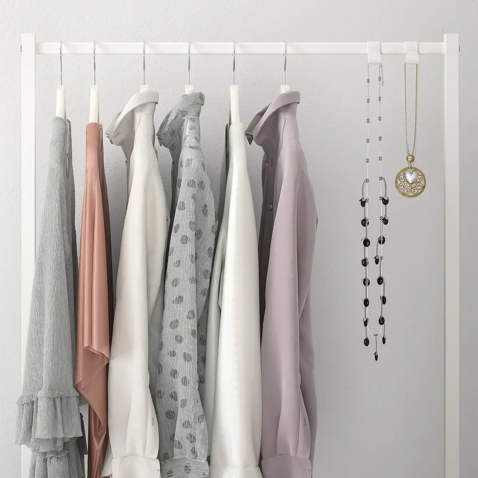 Closet rail with six hanging shirts in soft colours and two necklaces, showcasing clothing storage and organisation.