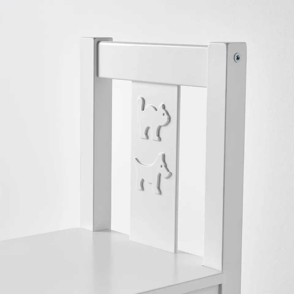 A white childrens chair made of durable materials like fiberboard and polystyrene with a simple kettle and cup design, against a plain wall.