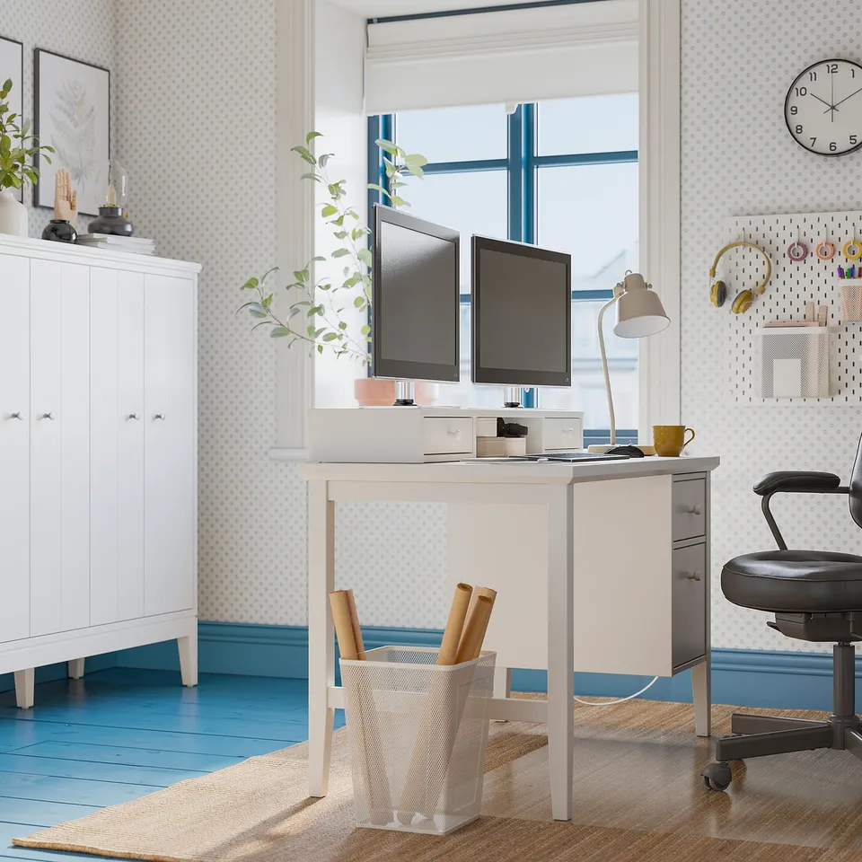 Home office with GULLABERG desk, dual monitors, office chair, mug, cabinet, natural light.