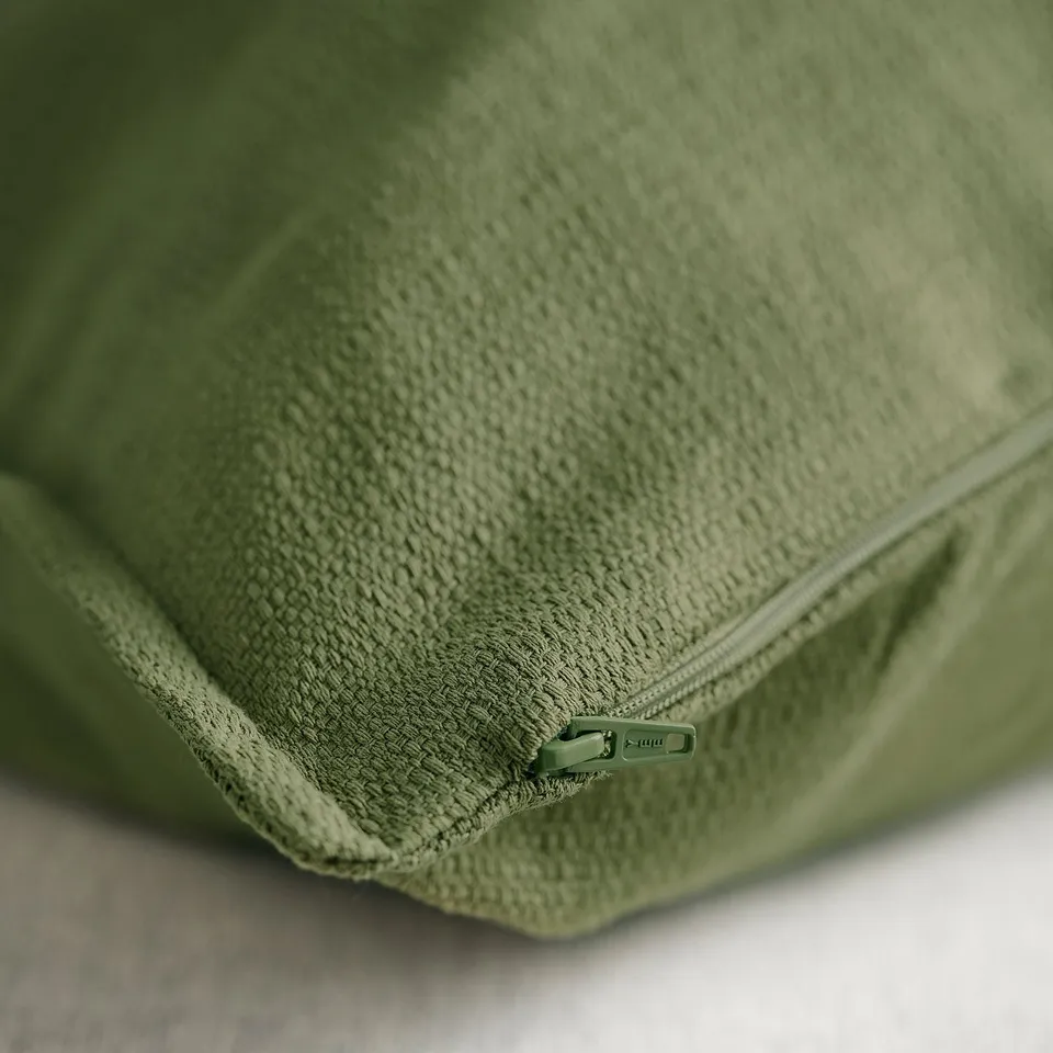Close-up of green cushion cover with quality zip, smooth texture.
